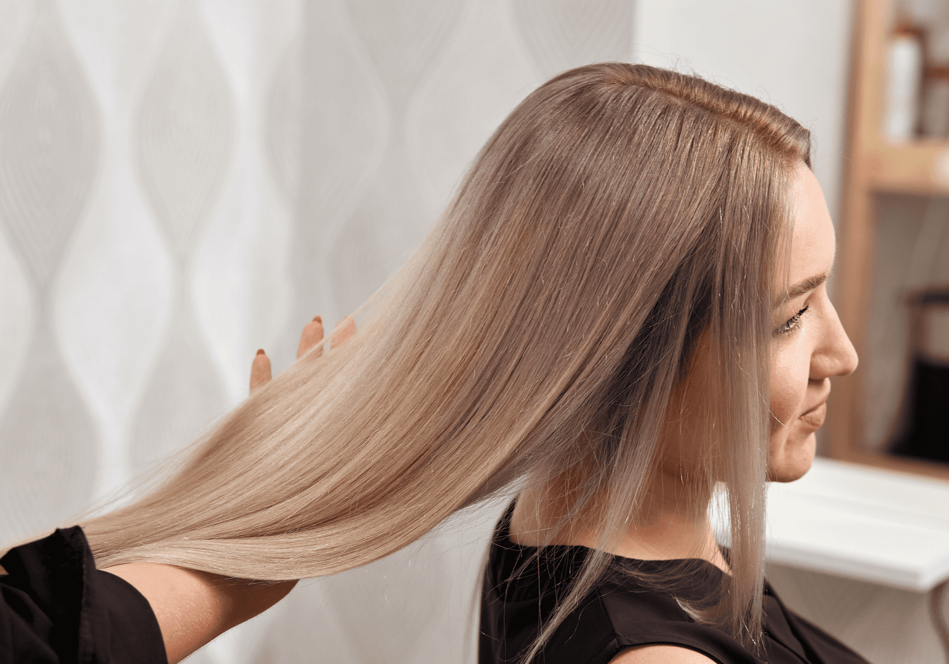 A stylist checking the smoothness of a client's long straight hair.